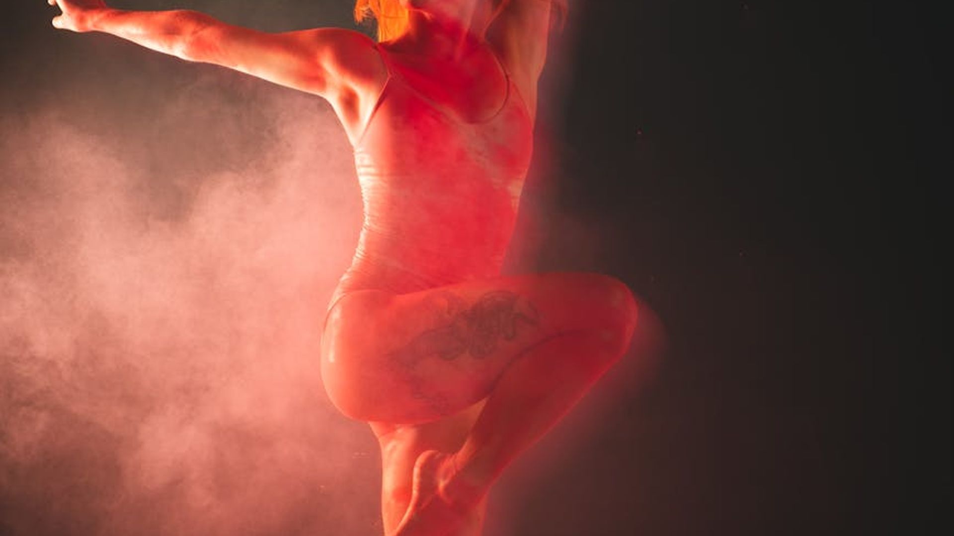 A person in a light-filled room performing a fluid, dynamic movement, suggesting energy and control.